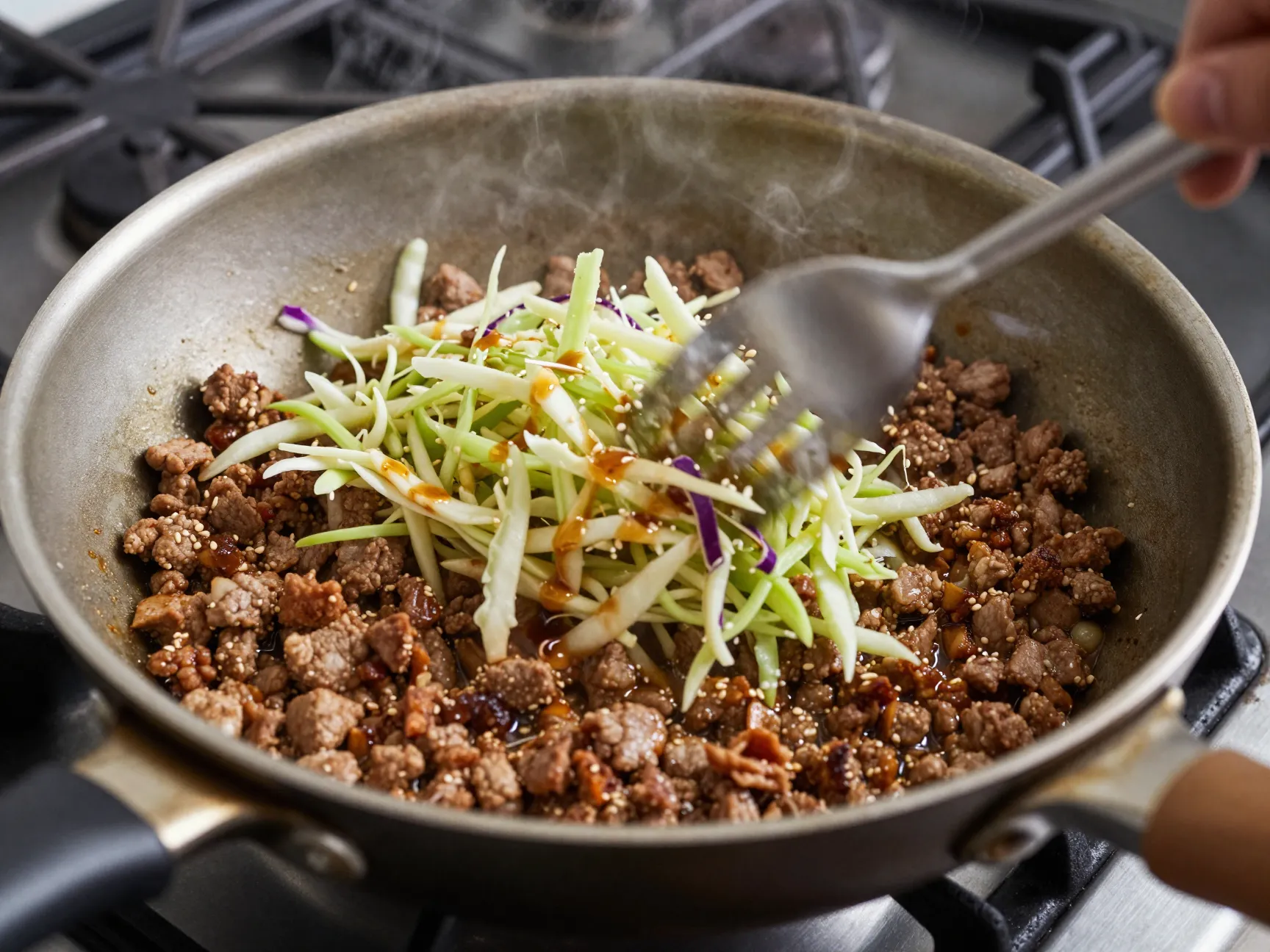 Ground pork and coleslaw stir fry in a skillet